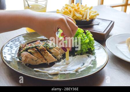 Girl Hand hält pommes frites. Fleisch, Salat und Sauce Stockfoto