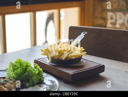 Pommes frites in der Pfanne auf Holztisch Stockfoto