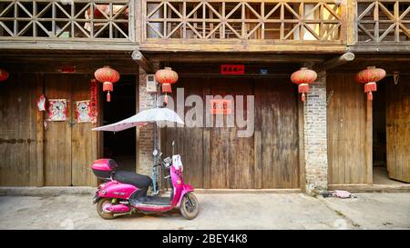 Xingping, China - 18. September 2017: Pink Scooter parkt vor einem Holzhaus in der Altstadt von Xingping. Stockfoto