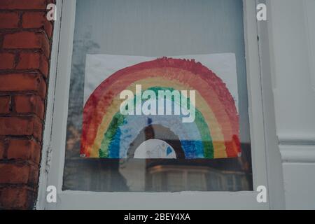 London, UK - 12. April 2020: Handgemachtes Regenbogenschild in einem Fenster eines Hauses in London, während Menschen sich gegenseitig unterstützen während der Sperrung wegen Stockfoto