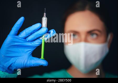 Die Ärztin hält eine Spritze und einen Impfstoff. Schwarzer Hintergrund. Coronavirus Covid-19 Schutz und Impfstoff. Stockfoto