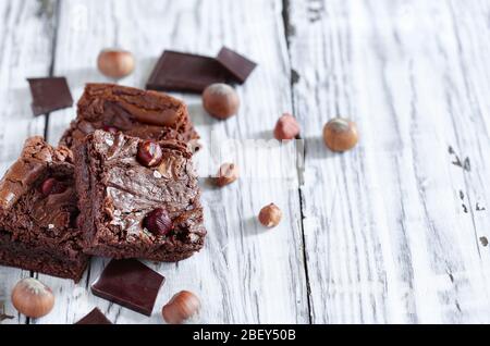 Frisch gemachte hausgemachte Brownies aus Schokolade Süßigkeiten und Haselnüssen auf einem weißen rustikalen Holztisch. Selektiver Fokus mit verschwommenem Hintergrund. Stockfoto