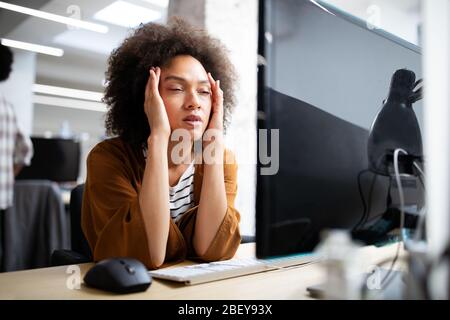 Überarbeitet und frustrierte junge Frau vor der Computer im Büro Stockfoto