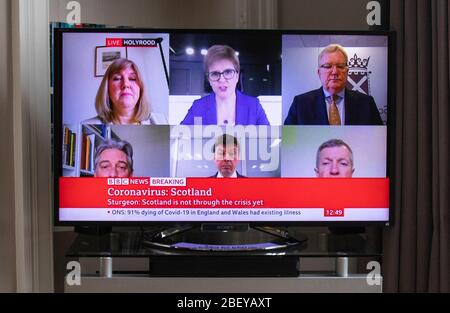 Schottlands erster Minister Nicola Sturgeon und andere Parteiführer werden im Fernsehen in einem Wohnzimmer in Edinburgh während der Übertragung einer "virtuellen" Sitzung der Fragen des Ersten Ministers gesehen. Die Führer aller Oppositionsparteien haben die Möglichkeit, sie aus der Ferne zu befragen, damit sie die Reaktion der Regierung auf die Krise des Coronavirus (COVID-19) genau untersuchen können. (Im Uhrzeigersinn von oben Mitte) Nicola Sturgeon, Jackson Carlaw, Präsidialbeamter Ken Macintosh, Richard Leonard und Alison Johnstone. Stockfoto