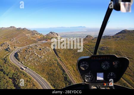 Luftaufnahme aus dem Inneren eines Hubschraubers Blick auf den Sir Lowrys Pass mit Blick auf den Tafelberg Stockfoto