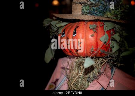 Eine gruselige trotzige Jack-o-Laterne Vogelscheuche trägt einen Strohhut und rosa Kleidung, halloween-Dekoration, Porträt, von der Seite gesehen Stockfoto