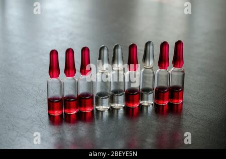 Glasampullen von Vitaminen der Gruppe B. neun Dosen von Vitaminen B12, B1 und B6 für die Injektion auf einem schwarzen Tisch. Nahaufnahme. Selektiver Fokus. Stockfoto