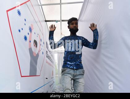 Guwahati, Assam, Indien. 15. April 2020. Ein Arbeiter, der in einen Corona Sanitisationstunnel kommt, bevor er in ein Quarantänezentrum am Sarusajai Sports Complex in Guwahati eintritt. Stockfoto