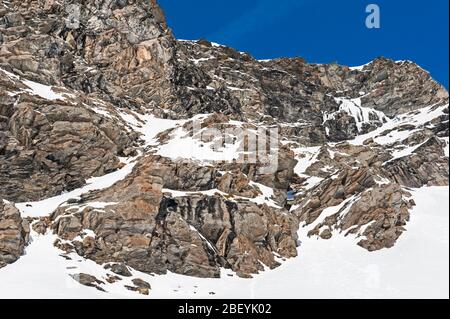 Zerklüftete alpine Felslandschaft mit gefrorenem Wasserfall, der mit Schnee und Eis bedeckt ist Stockfoto