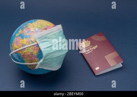 Medizinische Maske auf Globus mit portugiesischen europäischen Pass auf blauem Hintergrund setzen. Stockfoto