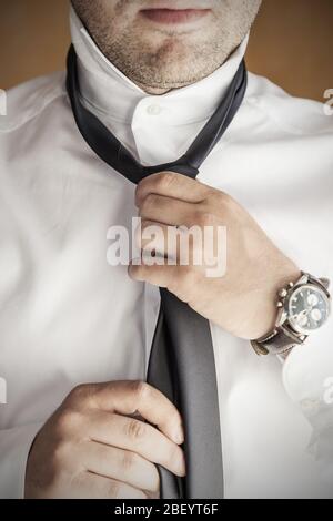 Nahaufnahme des Mannes in weißem Hemd Anziehen und Anpassung Krawatte am Hals - Menschen, Business, Mode und Kleidung Konzept. Stockfoto