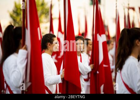 Izmir, Türkei - 29. Oktober 2016. Rote türkische Flaggen und junge Studentinnen halten sie bei der Zeremonie am Cumhuriyet Square Alsancak in Izmir. In Der Republik Stockfoto