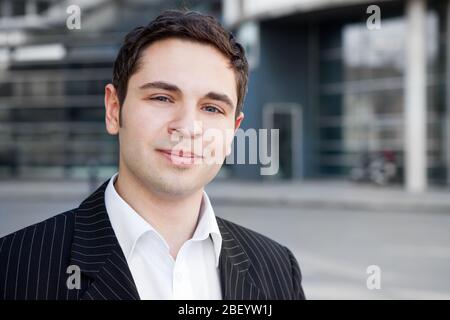 Der junge Geschäftsmann steht lächelnd in der Stadt Stockfoto