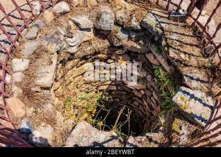 Arzachena, Sardinien / Italien - 2019/07/19: Archäologische Ruinen der nuraghischen Komplex La Prisgiona - Nuraghe La Prisgiona - mit Reste von Stein Brunnen Stockfoto