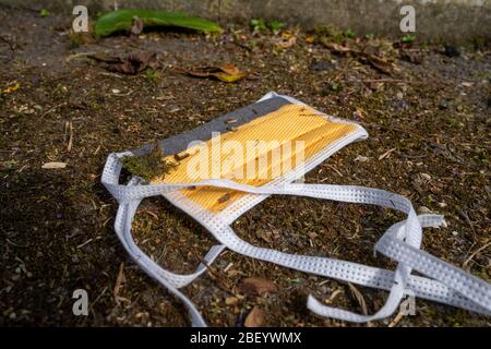 Nicht verwendete chirurgische Gesichtsmaske auf dem Boden im Schmutz während der Covid-19 Pandemie. Stockfoto