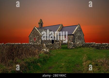 Die St. Peulan's Church, Anglesey, ist eine redundante Kirche aus dem 12. Jahrhundert. In diesem Fantasiebild wurden Himmel und Vordergrund verändert. Stockfoto