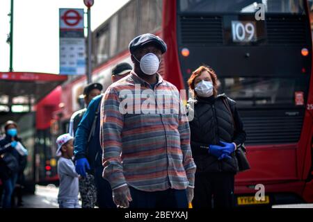 Menschen mit Schutzmaske warten in Brixton, South London, in der Schlange auf einen Supermarkt, während Großbritannien weiterhin gesperrt wird, um die Ausbreitung des Coronavirus einzudämmen. Stockfoto