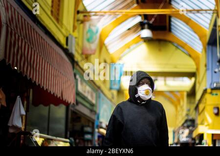 Ein Mann mit einer schützenden Gesichtsmaske geht durch den Brixton Market in South London, während Großbritannien weiterhin in der Lockdown-Richtung bleibt, um die Ausbreitung des Coronavirus einzudämmen. Stockfoto