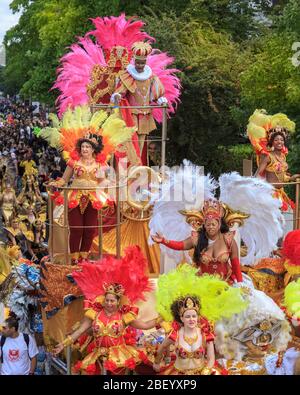 Farbenfrohe karibische Festwagen und Teilnehmer in Kostümen beim Notting Hill Karneval Straßenfest und Parade, London, Großbritannien Stockfoto