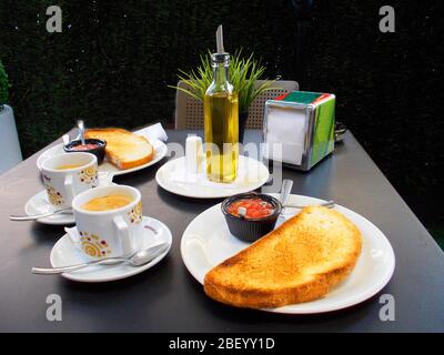 Spanisches Frühstück: Olivenöl, Toast, Tomaten und eine Tasse Kaffee. Spanien. Stockfoto