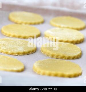 Quadratisches Bild von ungekochten hausgemachten Cookies warten auf den Ofen auf einer Trägerplatte. Aufnahme im Hintergrund mit selektivem Fokus, um Rezept-Overlay hinzuzufügen Stockfoto