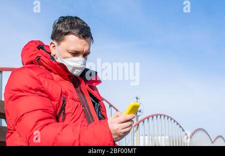 Ein kranker Mann, ein Mann in einer antiviralen medizinischen Maske sitzt auf einer Bank auf dem Bahnsteig eines Bahnhofs Stockfoto