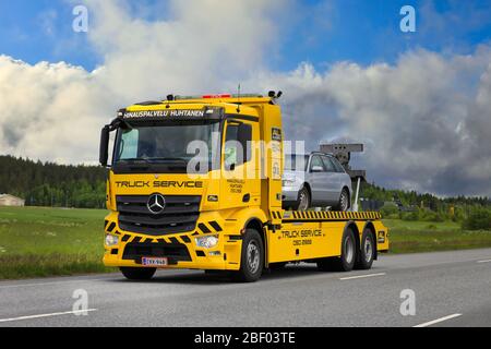 Gelbe Mercedes-Benz Abschleppwagen Hinauspalvelu Huhtanen trägt Pannenwagen auf Autobahn an einem Tag des Sommers. Forssa, Finnland. 23. Juni 2017. Stockfoto