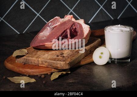 Rinderherz mit Zwiebeln, Gewürzen und saurer Sahne vor dem Kochen auf einem Holzbrett. Nahaufnahme. Stockfoto