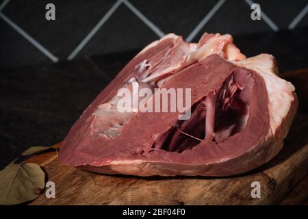 Rinderherz mit Zwiebeln, Gewürzen und saurer Sahne vor dem Kochen auf einem Holzbrett. Nahaufnahme. Food Concept Stockfoto