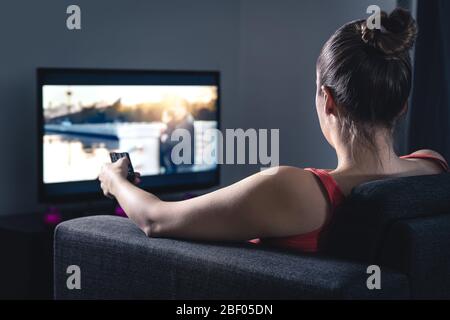 Frau streamt Filme oder schaut Serien an. Person, die die Smart tv-Fernbedienung verwendet, um Film auszuwählen oder den Sender zu wechseln. Stream oder Video on Demand (VOD). Stockfoto