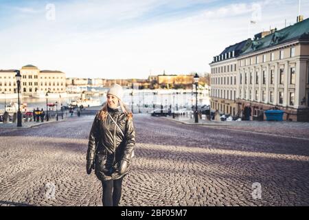 Stockholm im Winter. Person, die in der städtischen Stadtstraße in Schweden zu Fuß. Fröhliche Touristen, die sich die Gebäude in der Altstadt angeschaut haben. Frau in Gamla Stan. Stockfoto