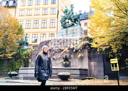Person, die im Winter oder Herbst in Stockholm und der Altstadt (Gamla Stan) spazieren geht. Gelbe Herbstfarben in Bäumen und Blättern. Frau im Urlaub in Schweden. Stockfoto