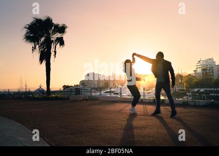 Paar tanzen auf der Straße. Spontaner spielerischer Moment mit Bewegung. Kerl und Mädchen mit Spaß und Dating. Stylische Trendsleute bei Sonnenuntergang. Urbanes Leben. Stockfoto