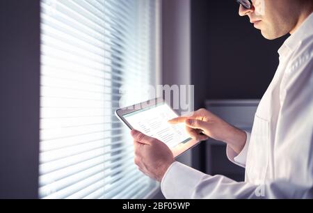 Arzt oder Geschäftsmann, der ein Tablet verwendet. Elektronische Krankenakte oder E-Mail-Nachrichten auf dem Bildschirm. Seriöse nachdenkliche Person mit Stress spät arbeiten. Stockfoto