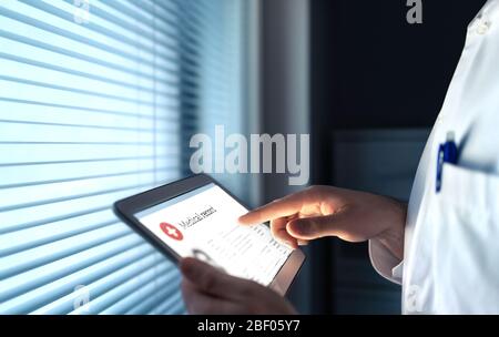Arzt, der elektronische Krankenakte (EMR) auf dem Tablet verwendet, um Gesundheitsinformationen für den Patienten zu lesen. Digitale Krankengeschichte oder -Bericht. Stockfoto