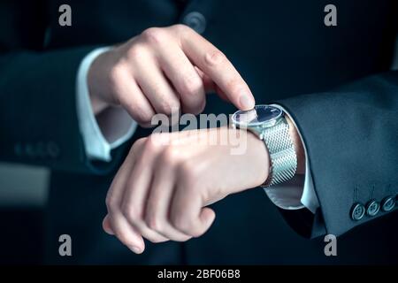 Sehen Sie sich das Handgelenk eines eleganten Geschäftsmanns an. Beschäftigter Geschäftsmann, der die Zeit betrachtet. Stress oder Eile bei der Arbeit. Person, die Anzug trägt. Stockfoto