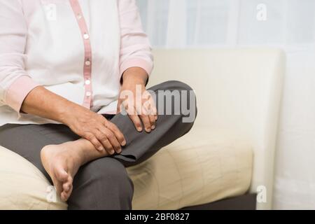 Bein Krampf alte Frau, die an Bein Krampf Schmerzen zu Hause, Gesundheitsproblem der Senior-Konzept Stockfoto
