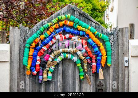 Brighton UK, 16. April 2020: Ein Regenbogen aus Flaschendeckeln, zur Unterstützung der NHS-Mitarbeiter landesweit, die ein Gartentor in Brighton schmücken. Kredit: Andrew Hasson/Alamy Live News Stockfoto