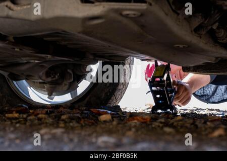 Kaukasus, Georgien, Tusheti Region, Omalo. Ein Mann stellt einen Wagenheber auf, um einen Platten Reifen auf der Straße nach Omalo - Tusheti zu reparieren Stockfoto