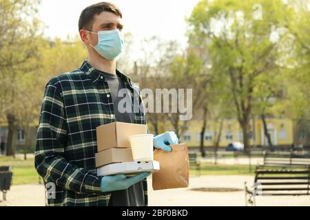 Kurier in Schutzmaske und medizinischen Handschuhen liefert Essen zum Mitnehmen Stockfoto