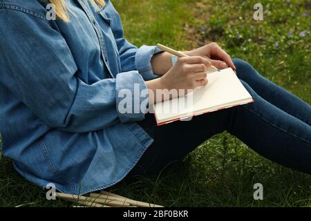 Mädchen zeichnet im Freien sitzen auf grünem Gras. Kreativitätskonzept Stockfoto