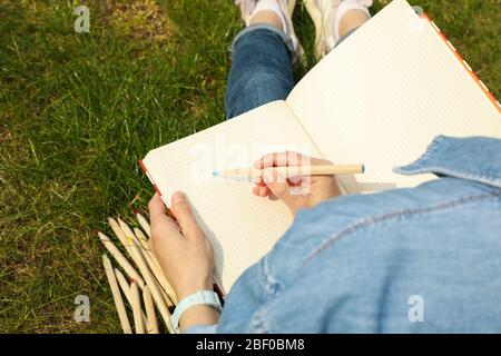 Mädchen zeichnet im Freien sitzen auf grünem Gras. Kreativitätskonzept Stockfoto