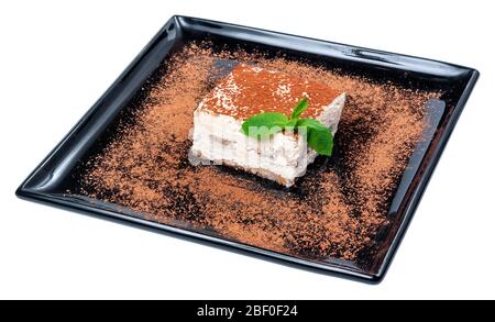 Tiramisu-Kuchen auf schwarzem Teller, leckeres italienisches Dessert mit Minze Stockfoto