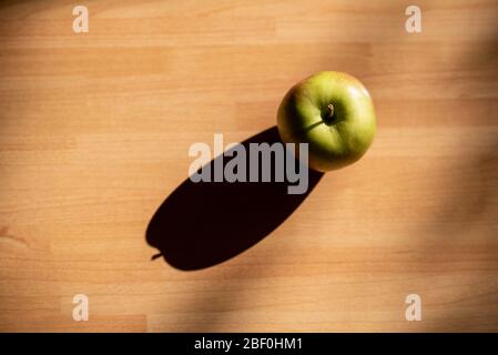Braeburn Apfel auf einem Holzbrett mit Abendlicht und Schatten Stockfoto