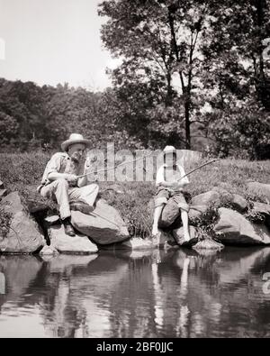 1930ER JAHRE JUNGE ANGELN IM TEICH MIT SEINEM GROSSVATER MIT ANGELRUTEN MACHEN AUS ZWEIGEN - A4789 HAR001 HARS FREUNDSCHAFT HALBE LÄNGE PERSONEN MÄNNER SENIOR MANN SENIOR ERWACHSENE B & W GLÜCK OLDSTERS SEINE PFEIFEN TABAK ERHOLUNG SCHLECHTE GEWOHNHEIT RAUCHER MIT ÄLTESTEN NIKOTIN VERBINDUNG GROSSVÄTER STROH HAT SÜCHTIG ENKEL ZWEIGE ANGELN ZUSAMMENARBEIT CORNCOB WACHSTUM JUVENILES ENTSPANNUNG STÄBE ZWEISAMKEIT SCHWARZ UND WEISS KAUKASISCHE ETHNIZITÄT GROSSVATER HAR001 ALTMODISCH Stockfoto