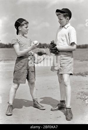 1930ER SAND LOT BASEBALL-SPIEL ZWEI PRE-TEEN JUNGEN BRÜDER TRAGEN BALL MÜTZEN UND SHORTS CATCHER HALTEN BALL GESPRÄCH MIT KRUG - B1988 HAR001 HARS WETTBEWERB INFORMATIONEN ATHLET LIFESTYLE BRÜDER ZU HAUSE LEBEN KOPIEREN RAUM FREUNDSCHAFT VOLLER LÄNGE MÄNNER PLANUNG ATHLETISCHE GESCHWISTER B & W MENGE SOMMERZEIT KRUG BERATUNG ERKLÄREN CATCHER UND VERNETZUNG ZU GESCHWISTER VERBINDUNG KAPPEN FREUNDLICH SAND LOT BALL KAPPEN BALL SPIEL BALL SPORT ZUSAMMENARBEIT JUGENDLICHE PRE-TEEN PRE-TEEN JUNGEN SAISON LÖSUNGEN ZWEISAMKEIT SCHWARZ UND WEISS KAUKASISCHEN ETHNIZITÄT HAR001 ALTMODISCH Stockfoto