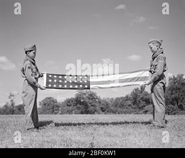 1950ER ZWEI TEENAGER PFADFINDER IN UNIFORM FALTEN EINE 48-STERNE-AMERIKANISCHE FLAGGE - B6113 HAR001 HARS B & W FREIHEIT FRÖHLICH FÜHRUNG STOLZ DIE GESCHWISTER UNIFORMEN JUNGE SCOUT VERBINDUNG THRIFTY KONZEPTIONELL HÖFLICH FREUNDLICH HILFSBEREIT FREUNDLICH EHRFÜRCHTIG TEENAGED VERTRAUENSWÜRDIG ZUSAMMENARBEIT JUGENDLICHE LOYALE PRE-TEEN PRE-TEEN JUNGE ROT WEISS UND BLAU STERNE UND STREIFEN ZWEISAMKEIT SEI VORBEREITET SCHWARZ UND WEISS TAPFERE KAUKASISCHE ETHNIZITÄT HAR001 GEHORSAM ALTMODISCH Stockfoto