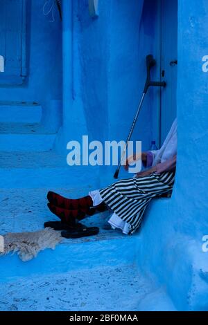 Chefchaouen, Nordmarokko, 10. Juni 2016. Eine ältere Frau in traditioneller marokkanischer Kleidung ruht an der Tür. Stockfoto