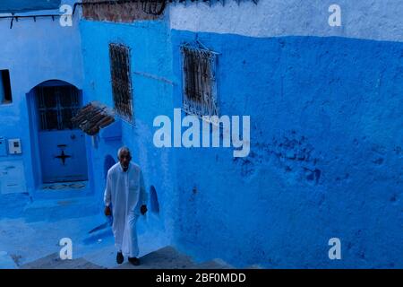 Chefchaouen, Nordmarokko, 10. Juni 2016. Ein alter Mann in traditioneller marokkanischer Kleidung, auf einer Treppe in einer der Straßen der blauen Stadt. Stockfoto