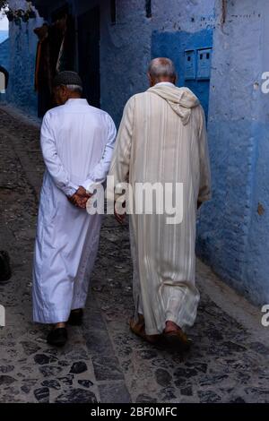 Chefchaouen, Nordmarokko, 10. Juni 2016. Zwei älteste, in traditioneller marokkanischer Kleidung, spazieren auf einer der Straßen der blauen Stadt. Stockfoto